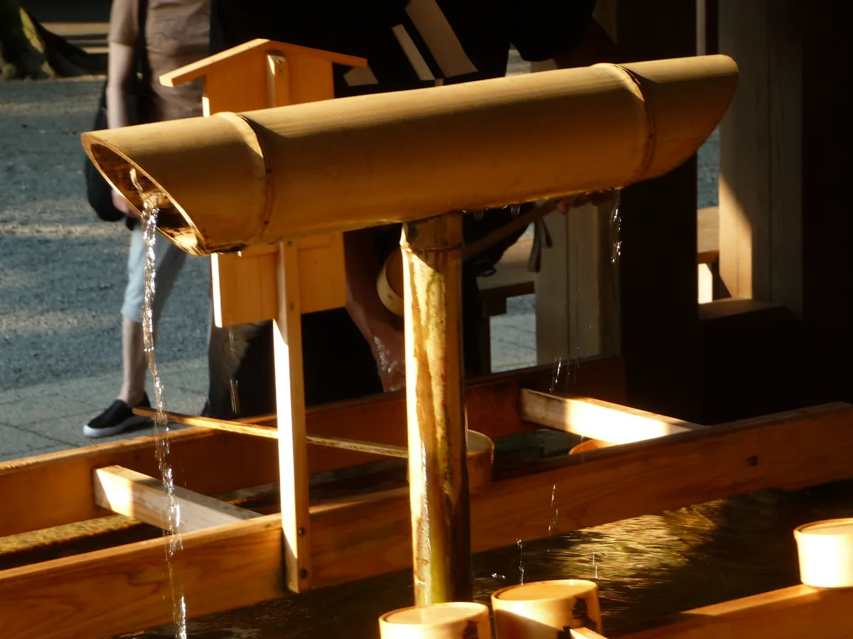 A bamboo ladle pouring water at the temizuya purification pavilion of Meiji Shrine