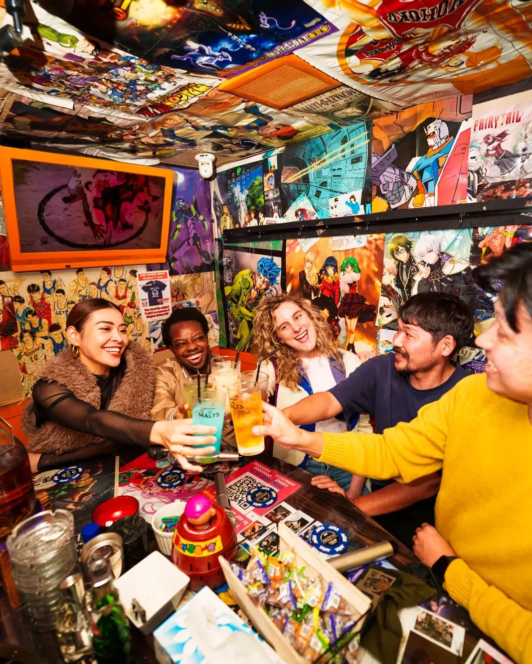 Guests raising glasses inside a tiny, poster-covered Golden Gai bar with their guide